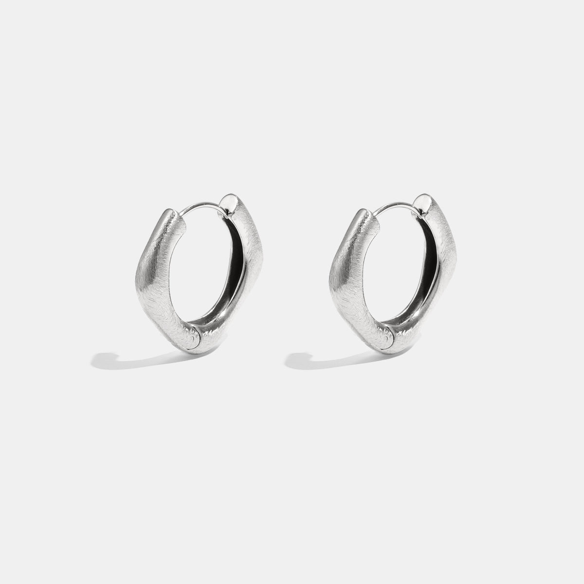 A pair of silver Astra hoop earrings with a unique square shape and rounded edges.