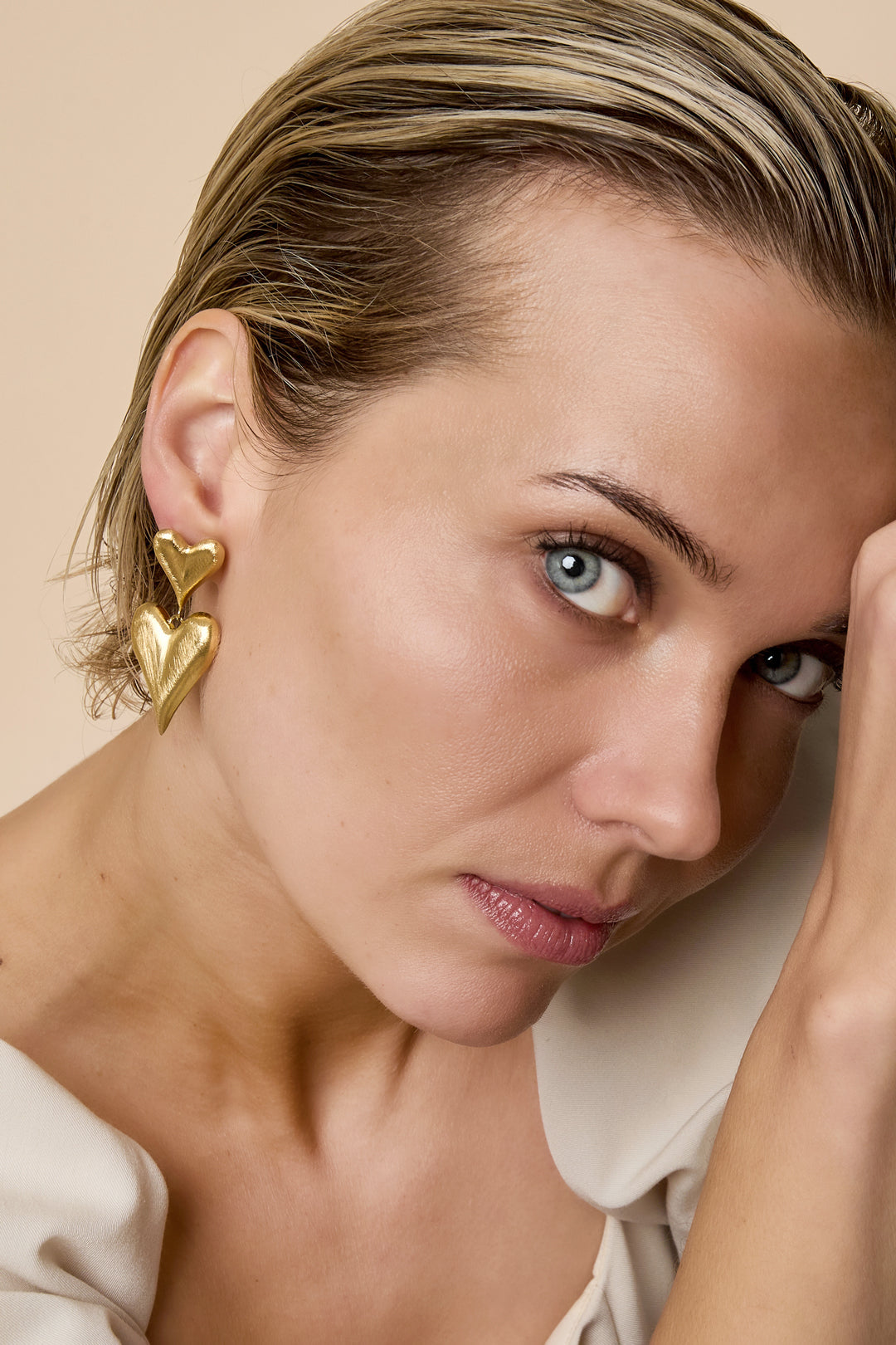 Gold heart drop earrings with a smaller heart above a larger heart.
