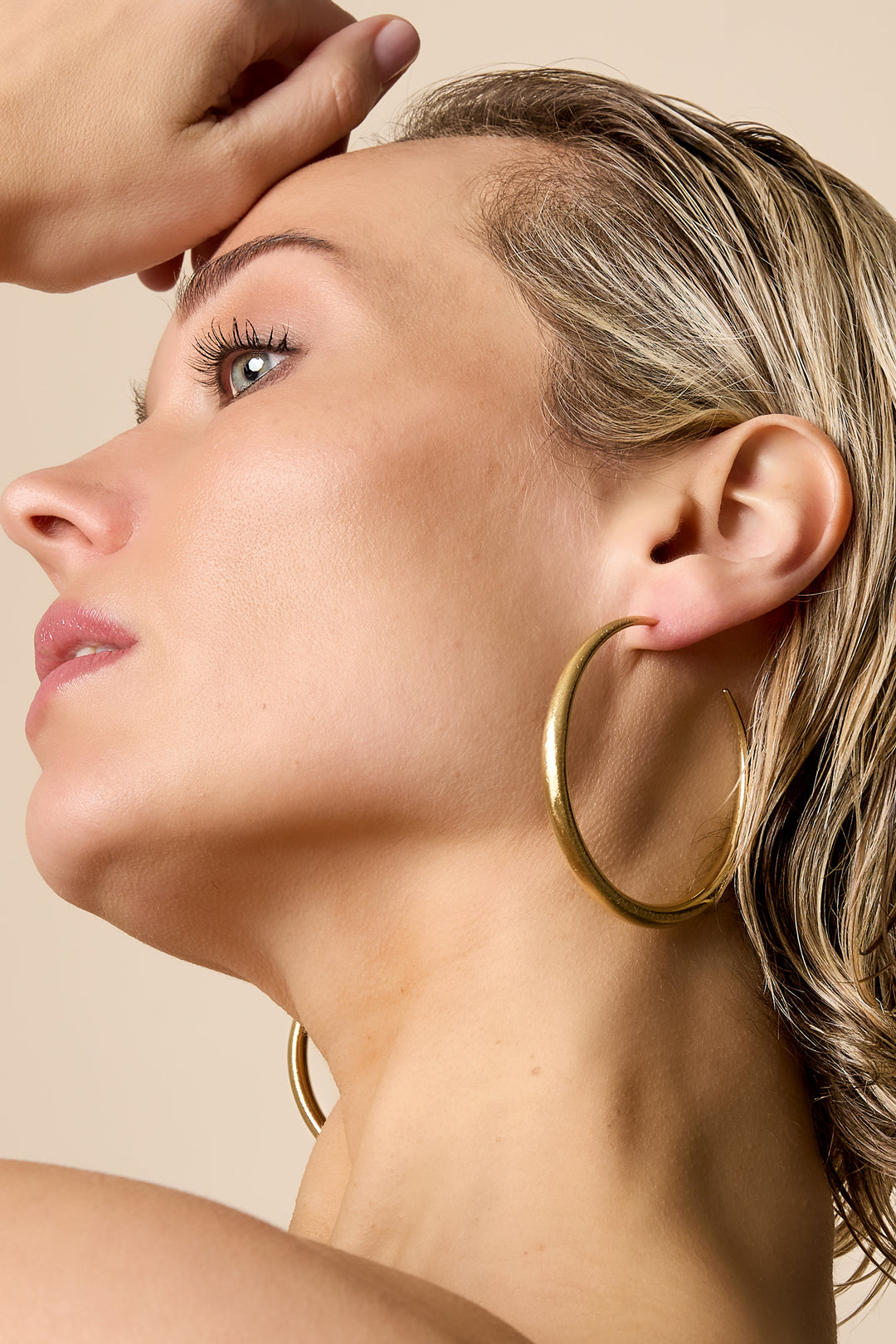 Gold hoop earrings worn by a woman, showing the detail of the jewelry.