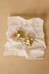 Aurelia stud earrings in gold with pearl accents on crumpled white paper.