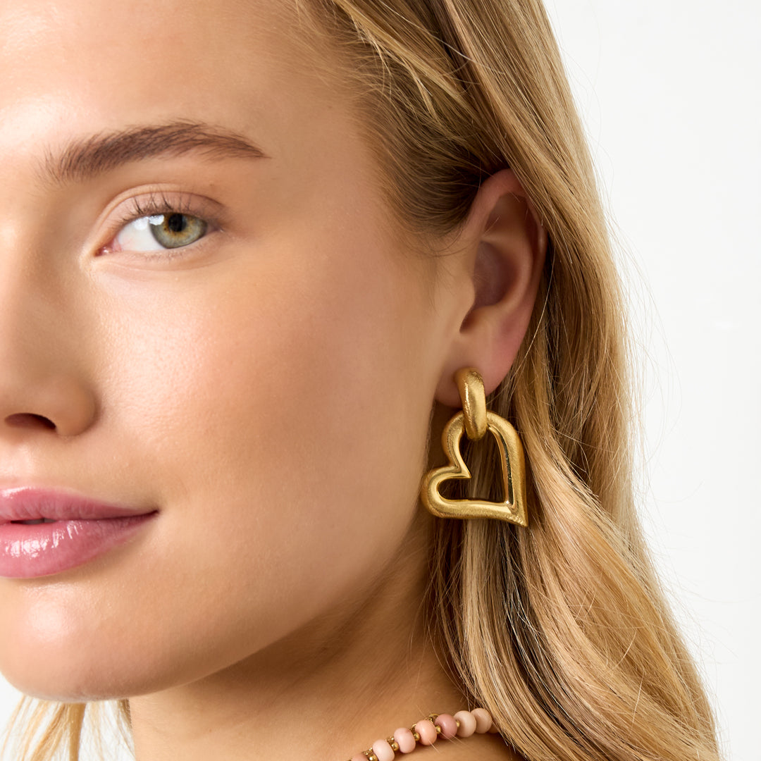 Gold heart drop earrings with a textured finish, worn by a model.