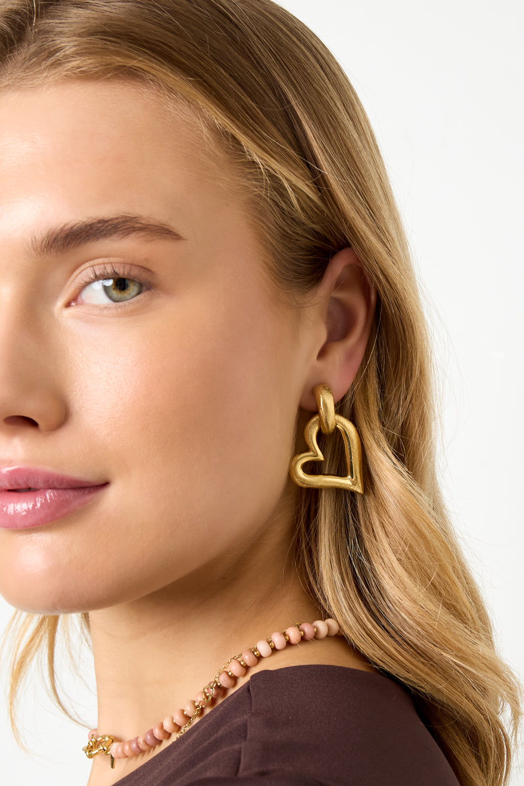 Gold heart drop earrings with a textured finish, worn by a model.