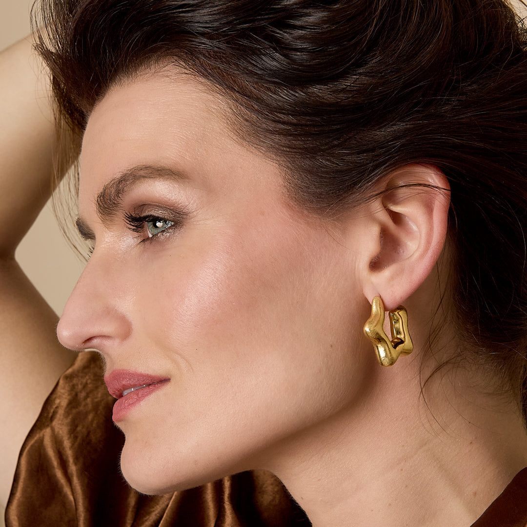 Gold celestial star hoop earrings with a unique, abstract shape.