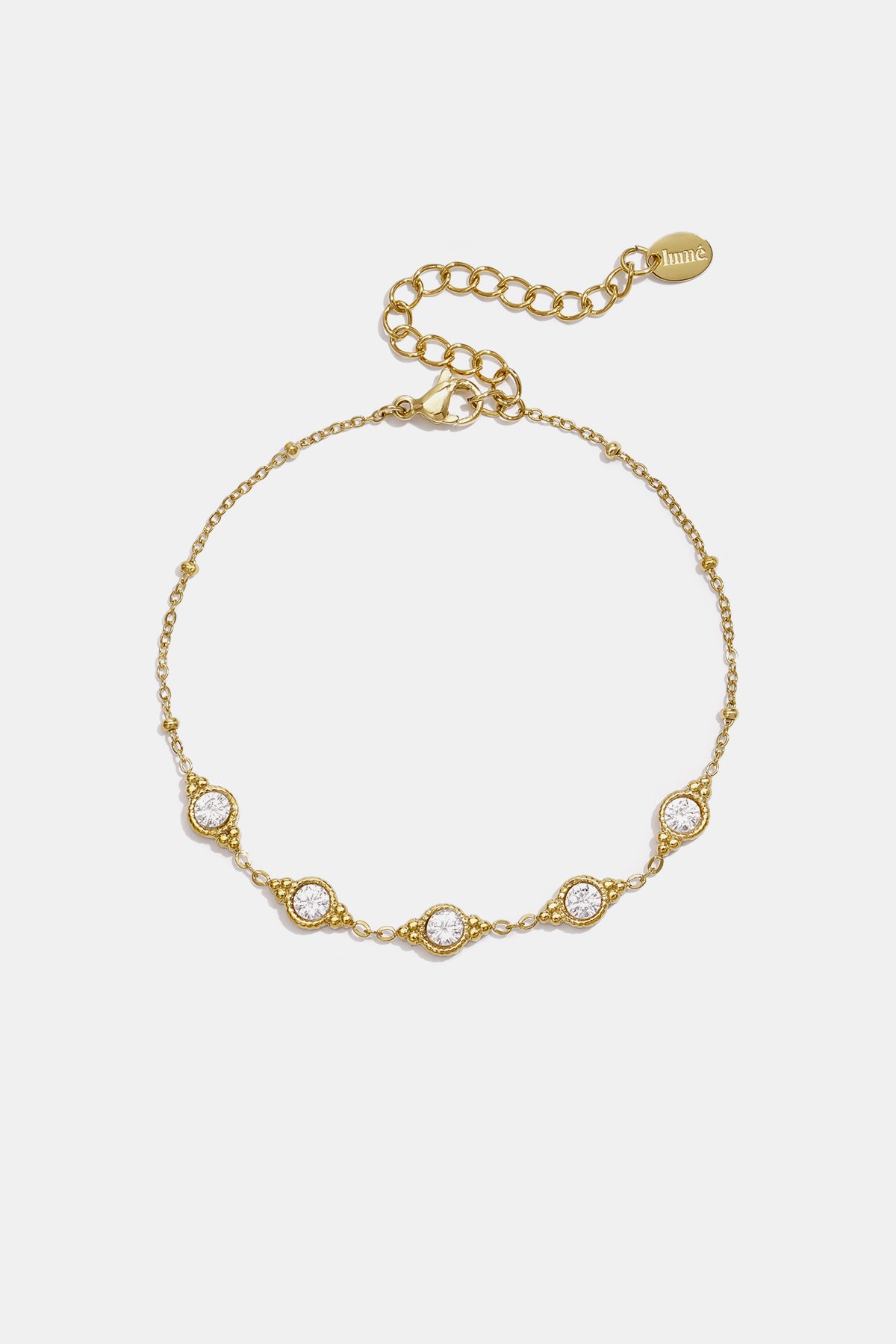 Gold geometric charm bracelet with five clear stones and beaded accents.