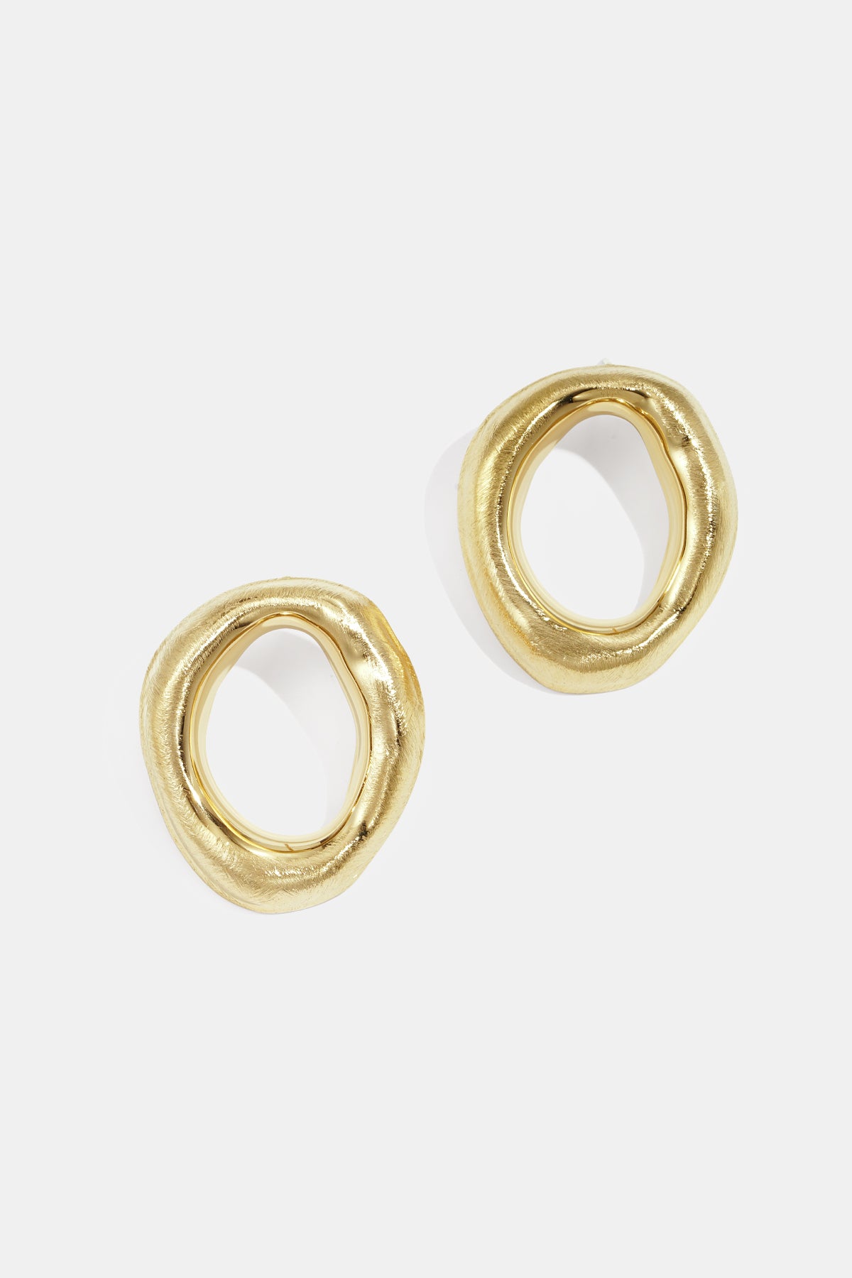 Two gold-toned, irregular-shaped stud earrings with a brushed finish.