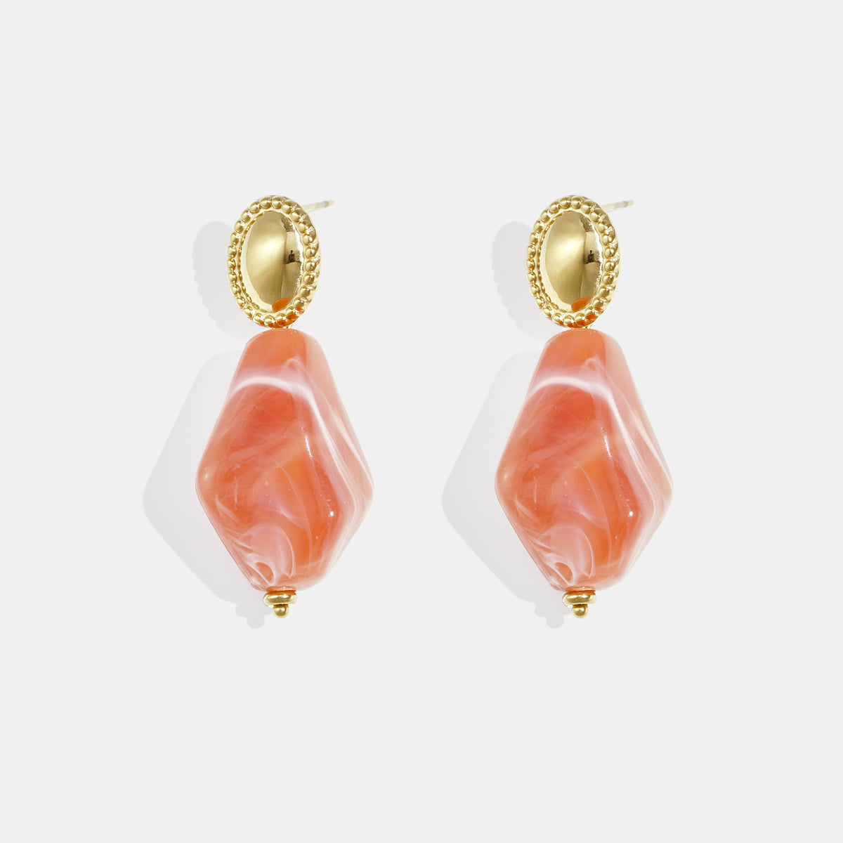 Pair of orange irregular diamond-shaped earrings with gold oval tops.