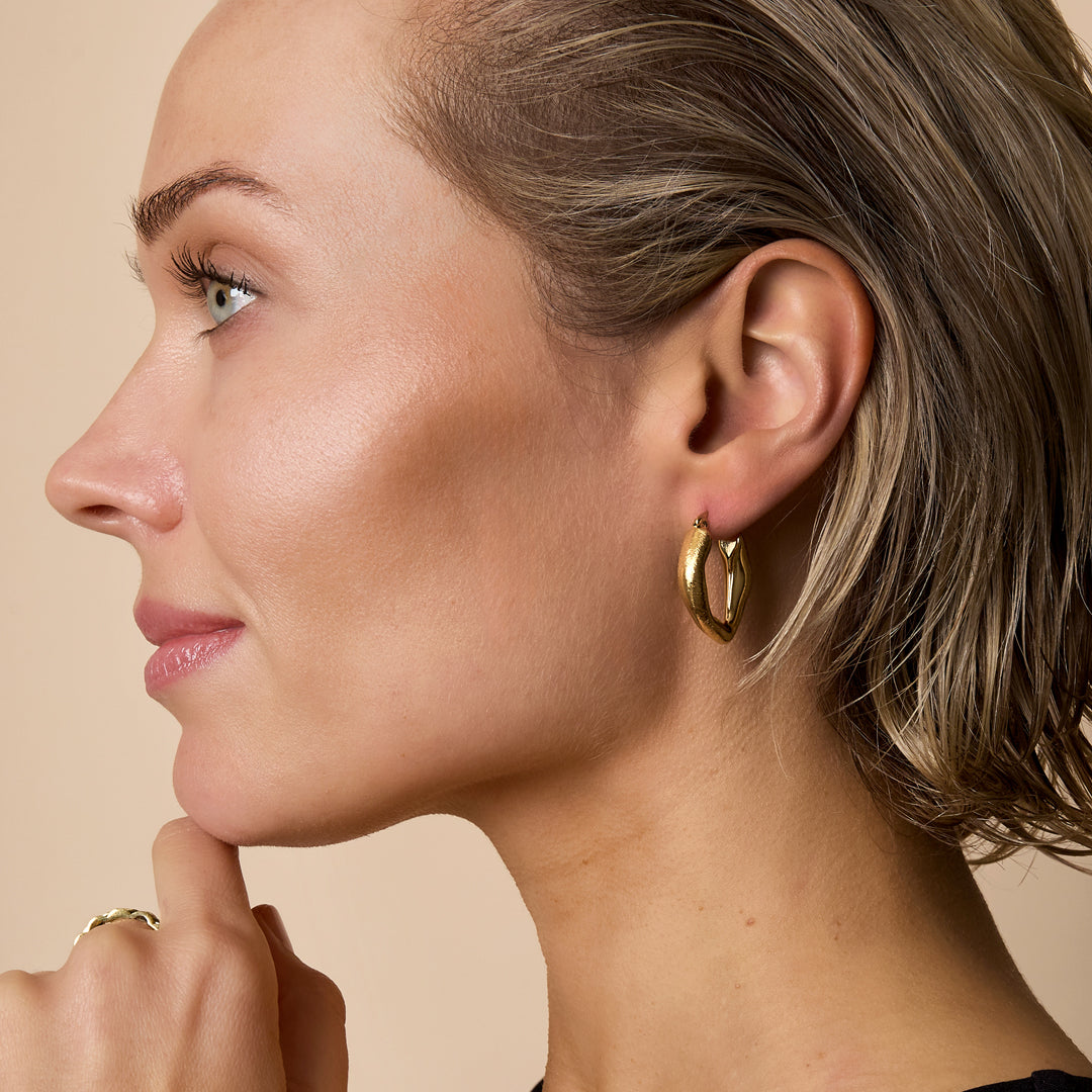 Aurelia Hoop Earrings: Gold-toned, heart-shaped hoop earrings with a shiny finish.