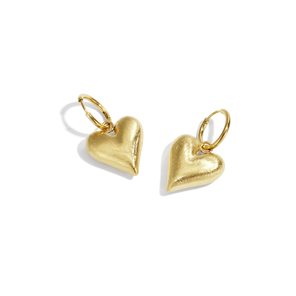 Gold heart drop earrings with hoop closures on a white background.
