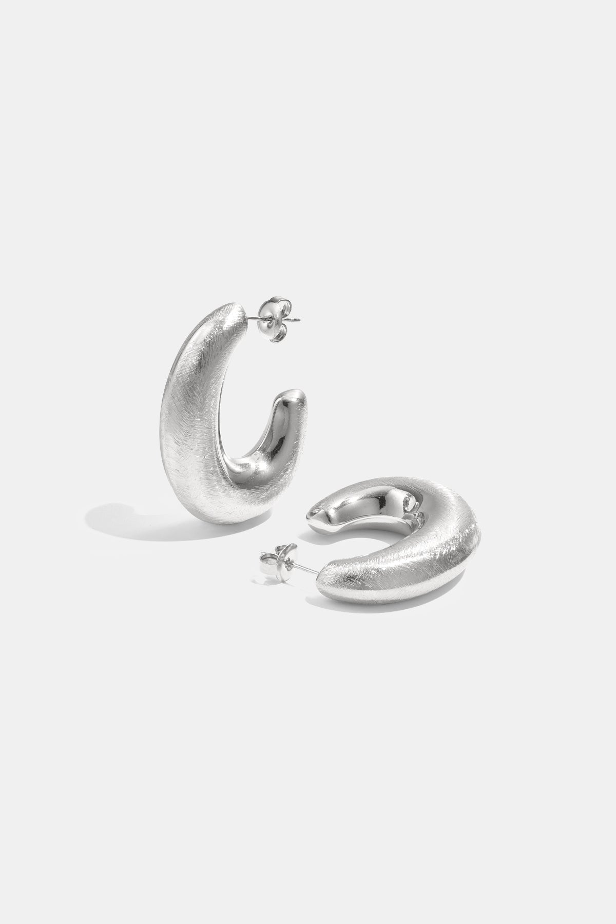 A pair of brushed silver Aurelia hoop earrings on a white background.