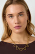 Gold chain necklace with heart pendants and gold hoop earrings on a woman