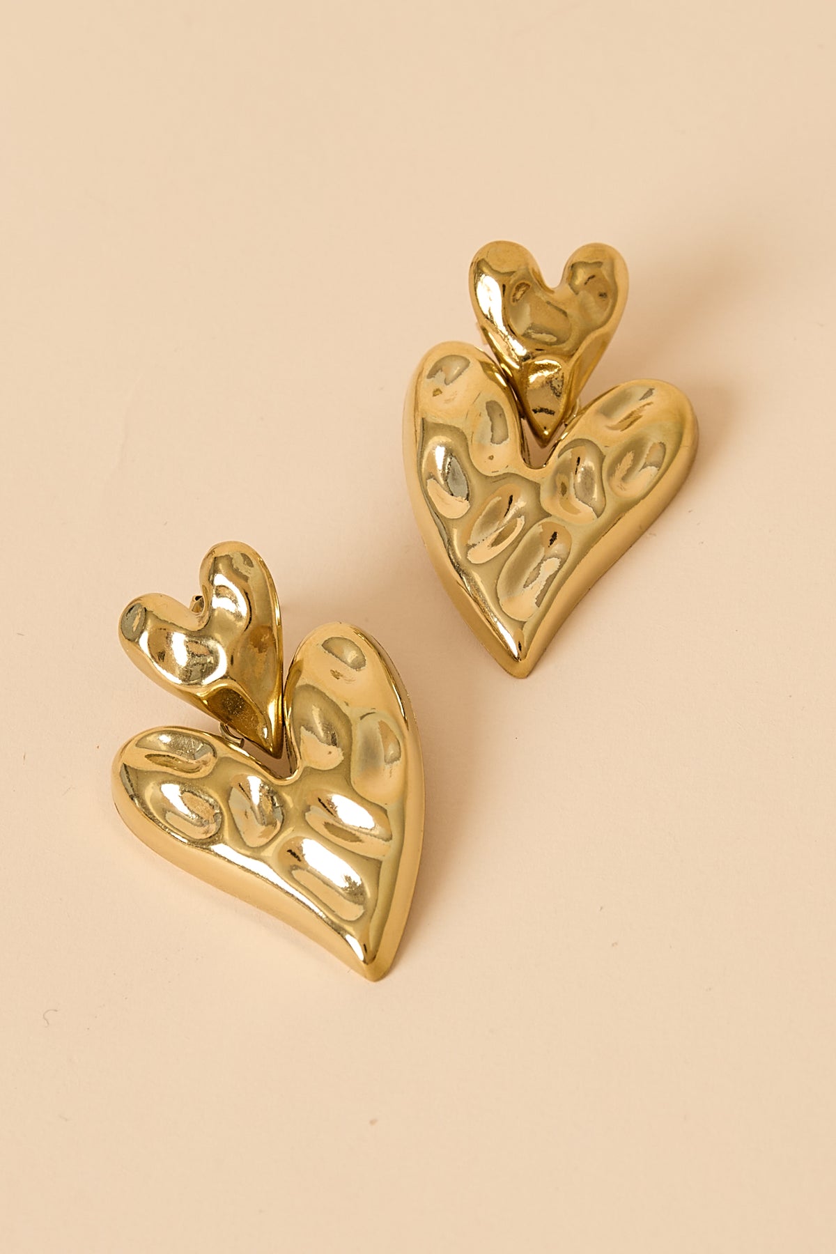 Gold stacked heart stud earrings with textured surface.