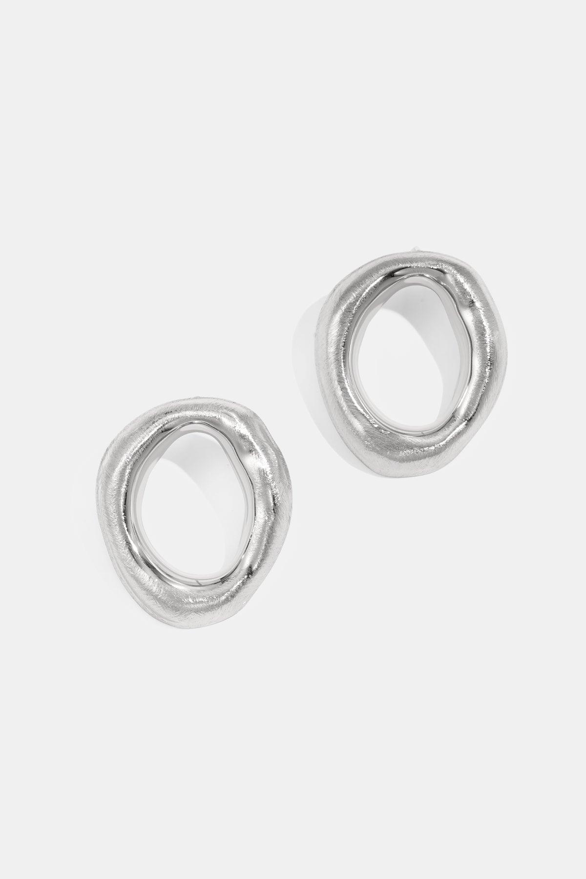 Two silver stud earrings with an irregular, organic shape and a brushed finish.