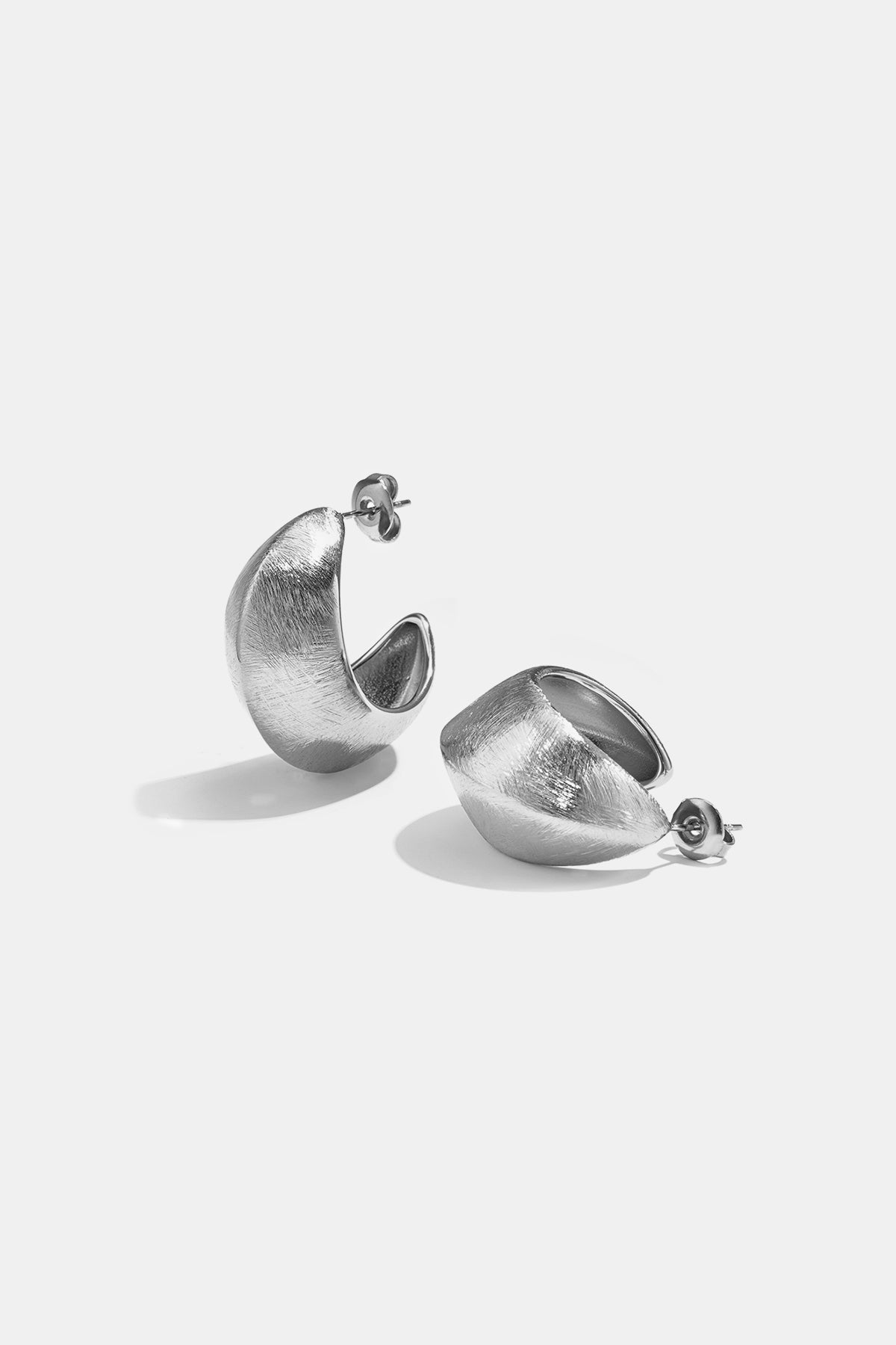 Two silver Aurelia hoop earrings with a textured finish on a white background.