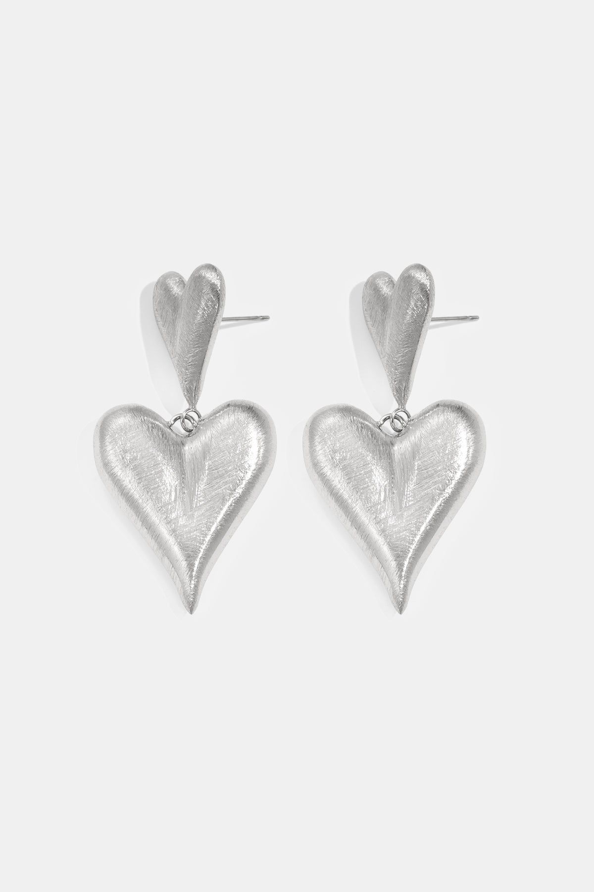 Silver heart drop earrings with a brushed finish, featuring a smaller heart stud connected to a larger dangling heart.