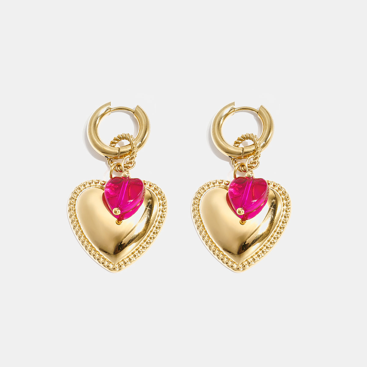 Gold heart hoop earrings with a pink heart bead accent.
