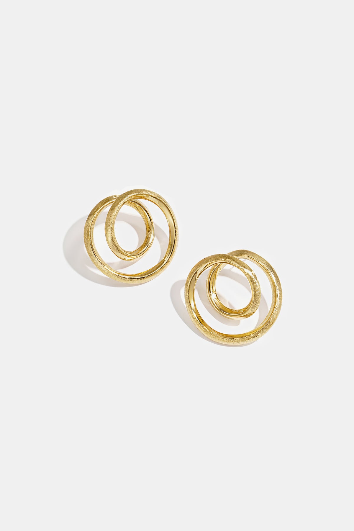 Two gold spiral circle stud earrings on a white background.