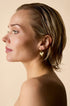 Gold heart drop earrings on a woman's ear.
