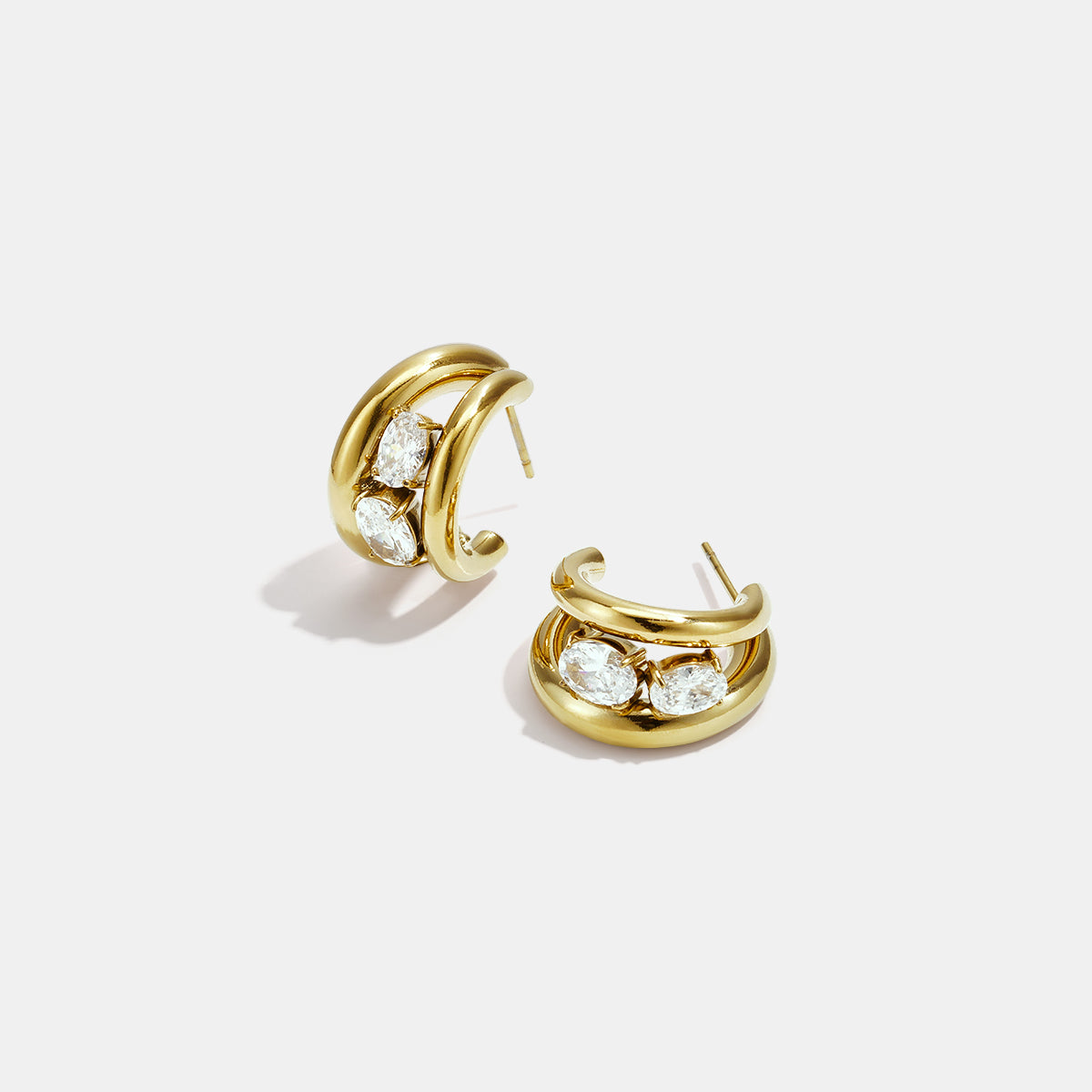 Gold hoop earrings with three clear oval stones set in each.