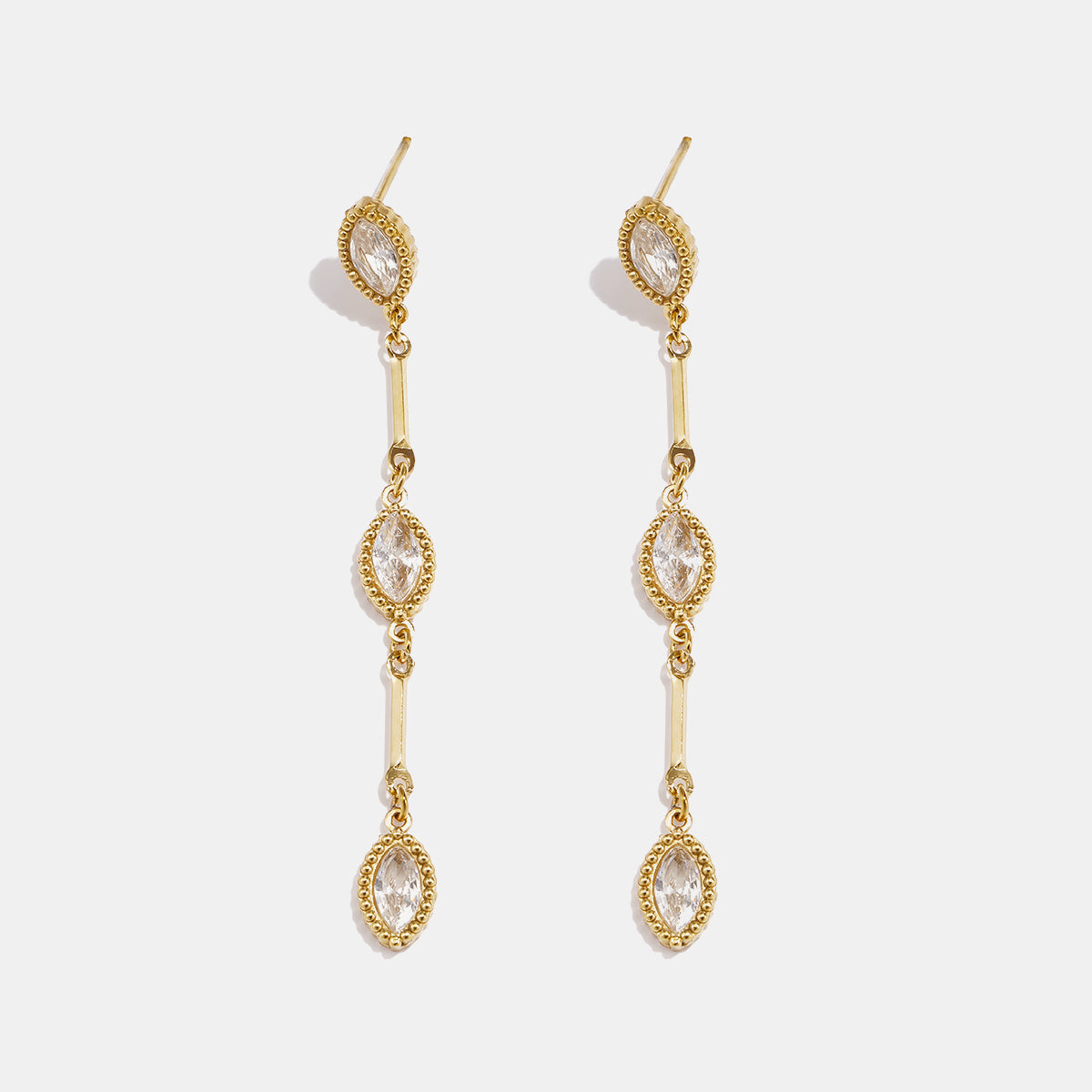 Gold dangle earrings with three marquise-shaped clear stones linked by gold bars.