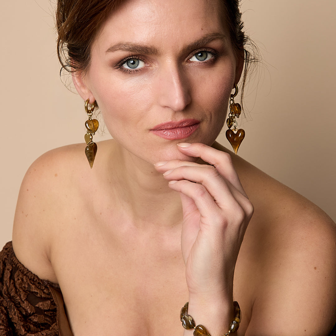 Gold-tone earrings with dangling amber-colored heart charms.