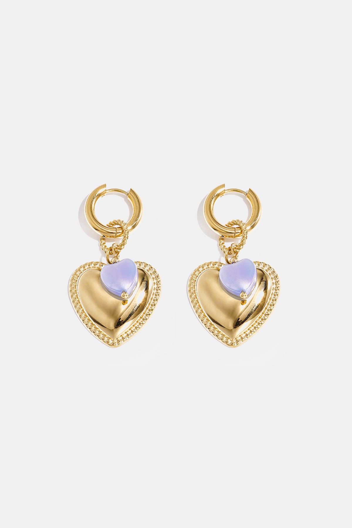 Gold hoop earrings with a large gold heart pendant and a small blue heart bead.