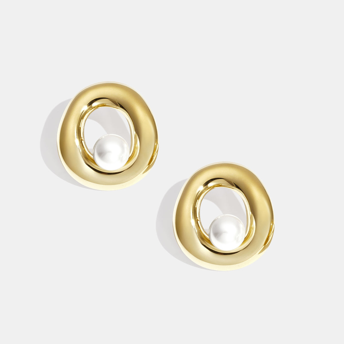 Gold circle stud earrings with a pearl accent inside the circle.