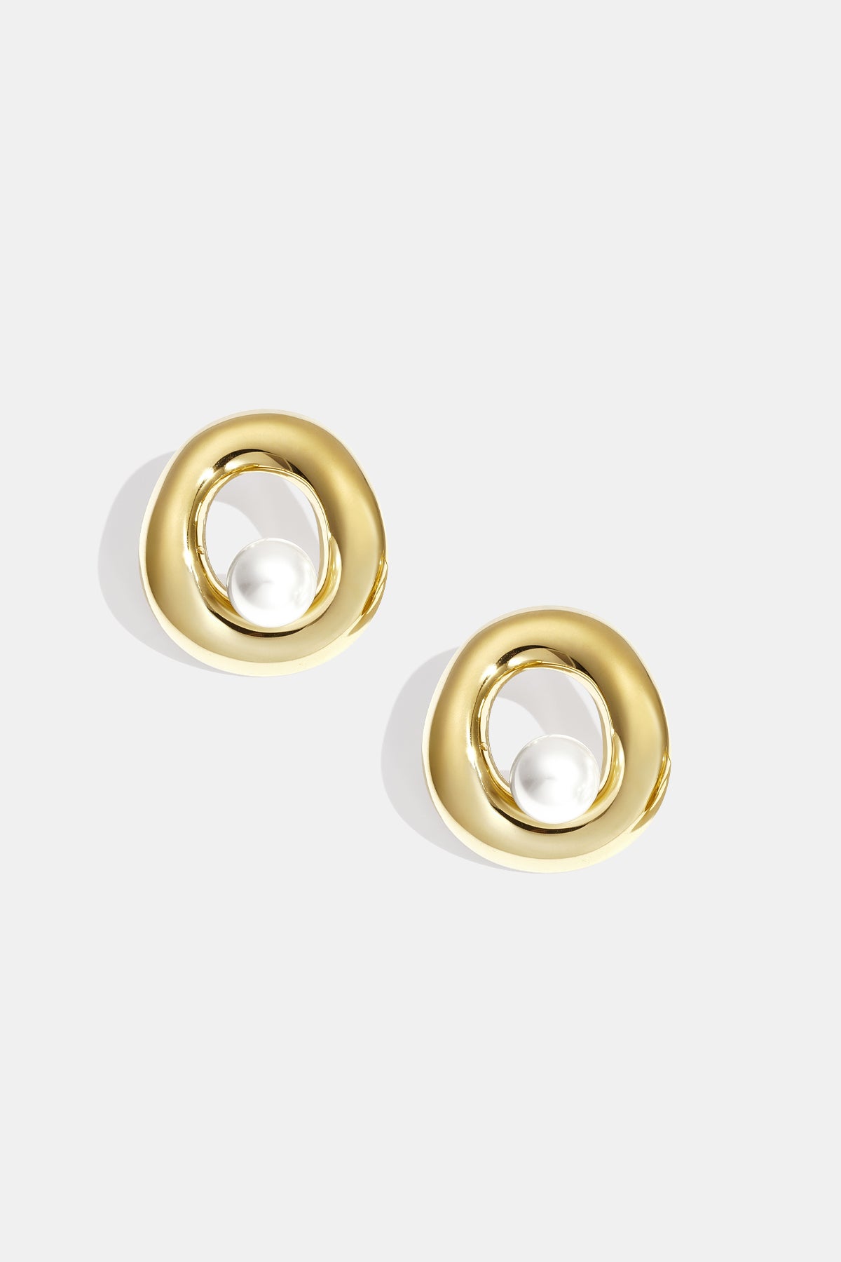 Gold circle stud earrings with a pearl accent inside the circle.