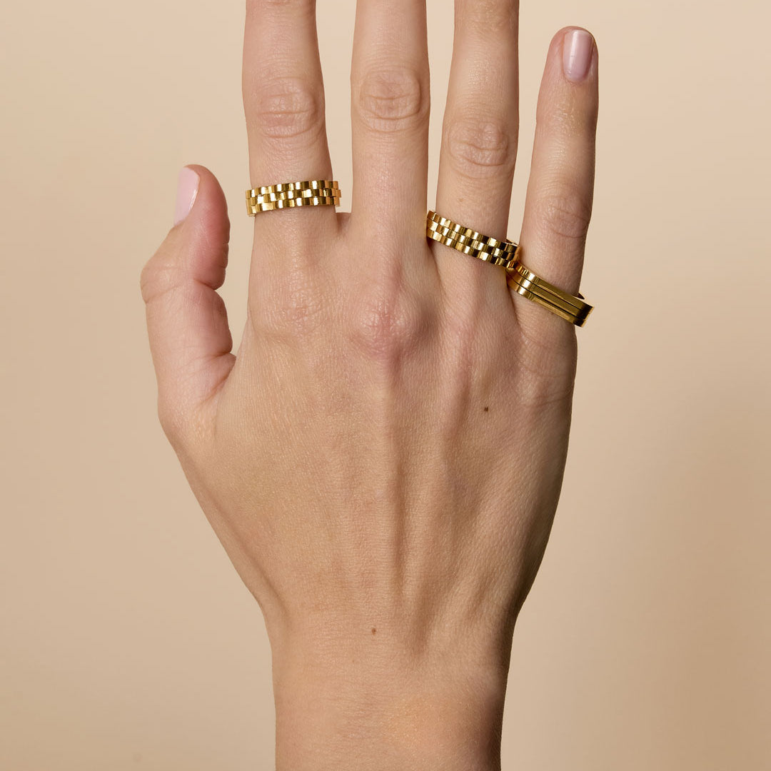 Gold-plated stainless steel ring with a minimalist rectangular design on a hand.
