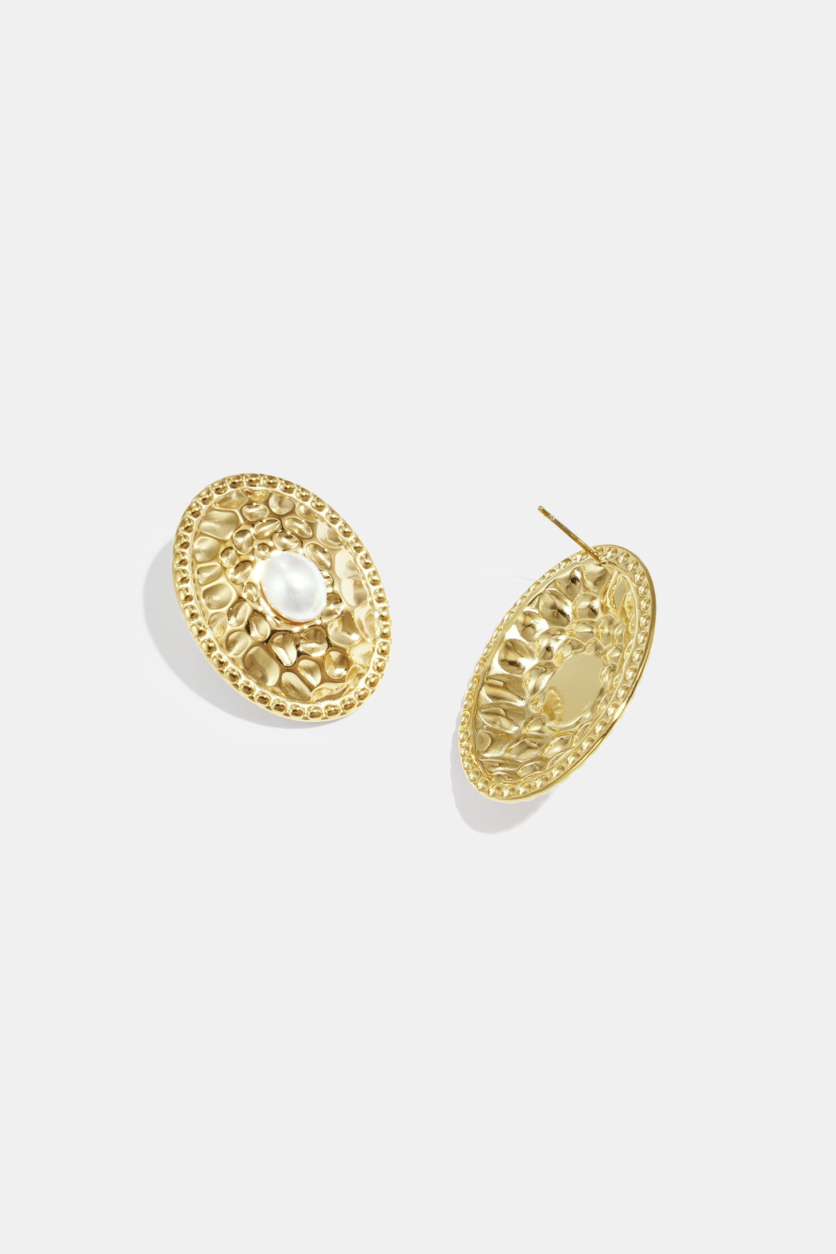 Gold oval stud earrings with hammered texture and a pearl accent.
