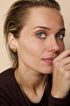 Gold heart-shaped stud earrings on a woman's ear.