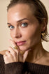 Gold ring with a heart shape and a zircon gemstone on a woman's finger.