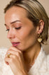 Gold heart drop earrings with rhinestones on a woman's ear.