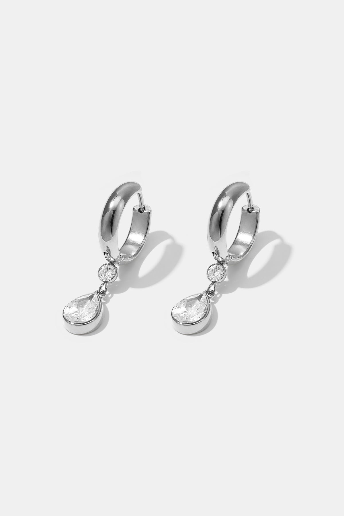 Silver hoop earrings with a dangling pear-shaped zircon and two small round zircons.