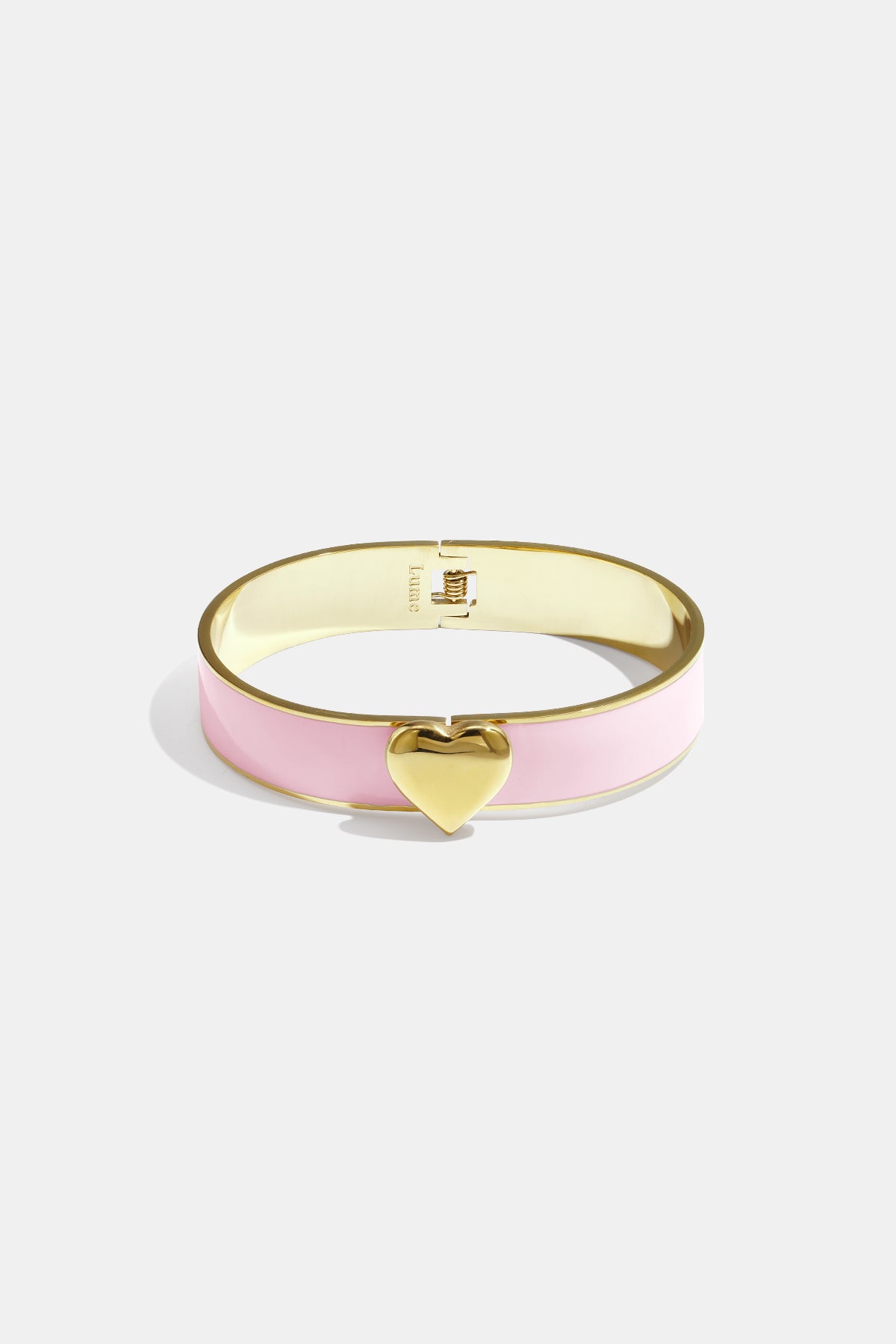 Gold bangle bracelet with pink enamel band and a gold heart charm.