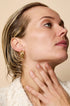 Gold Astra Hoop Earrings on a woman's ear, showcasing their intertwined design.