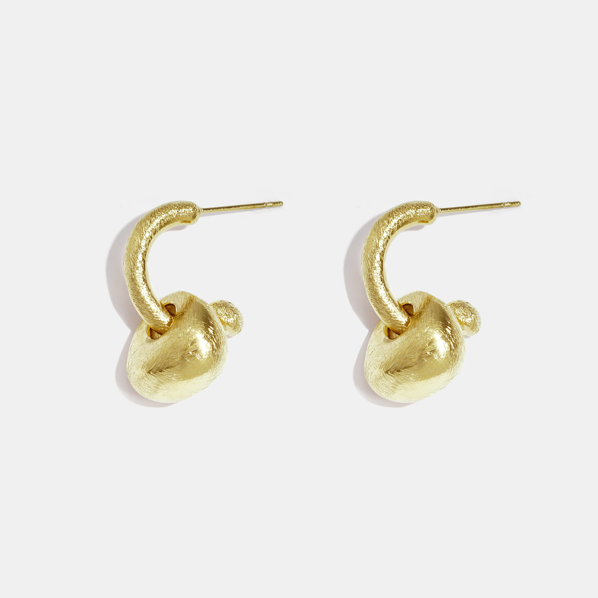 Gold-colored, matte finish drop earrings with irregular sculptural shapes.