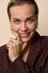 Gold ring with intertwined lines and a central zircon stone, worn on a woman's finger.