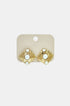 Gold geometric stud earrings with three pearls on a beige card.
