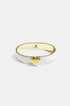 Gold heart charm on a white and gold bangle bracelet.