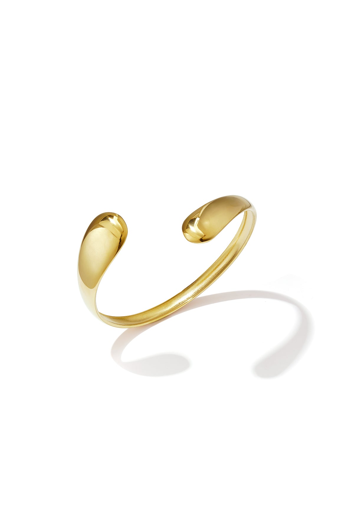 Gold irregular cuff bracelet with a polished finish, casting a shadow on a white background.