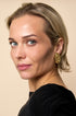 A woman wears irregular gold stud earrings and a gold necklace.