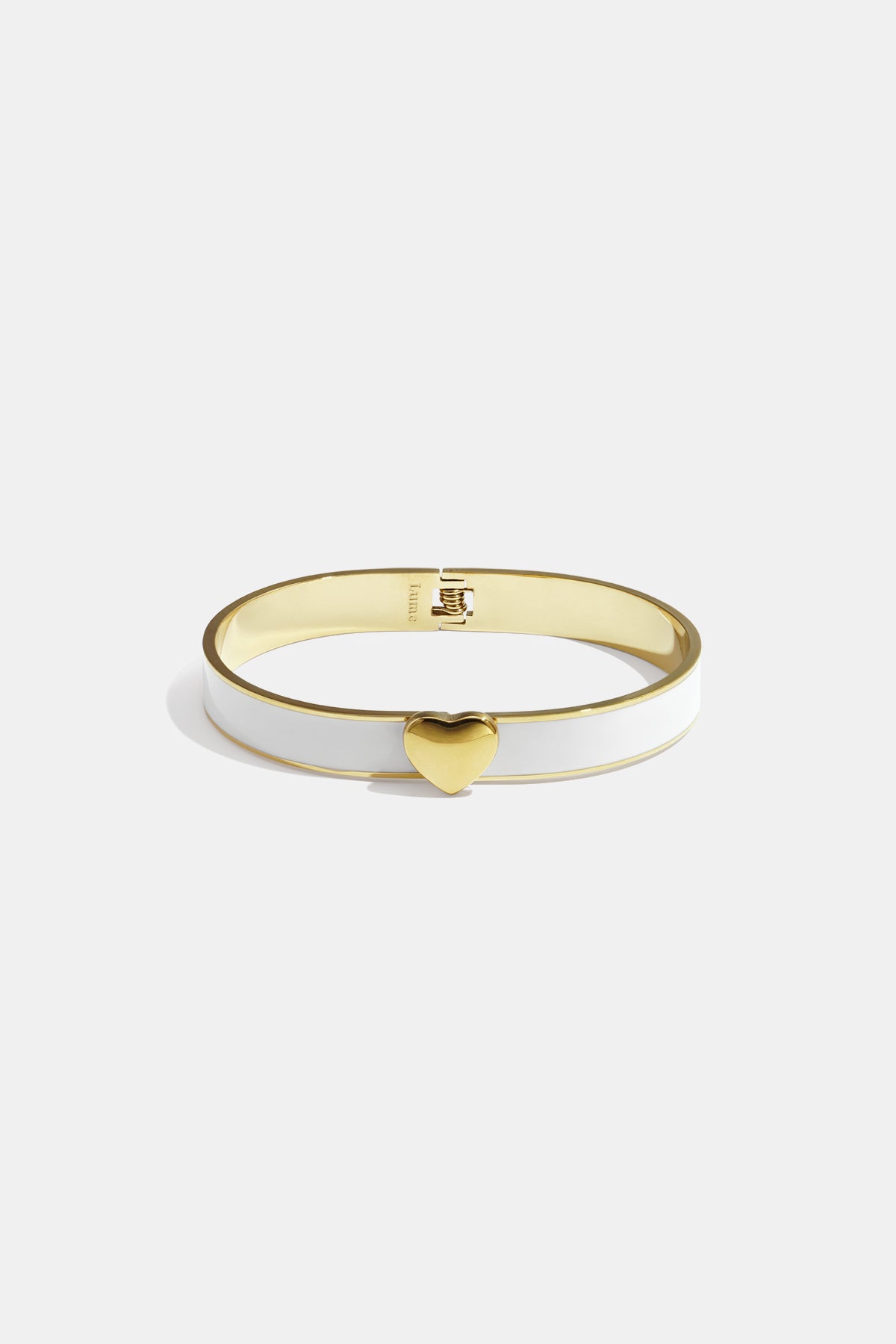 Gold-tone bangle with white enamel and a gold heart charm.