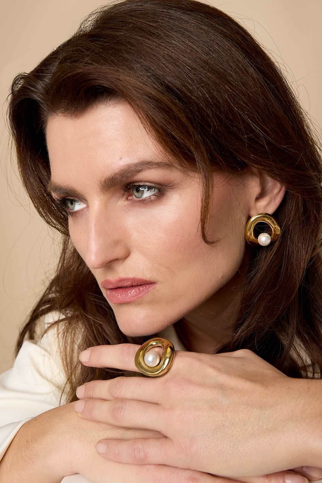 Gold statement ring with a pearl accent on a woman's hand.