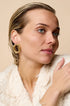 Gold irregular stud earrings on a woman's ear.