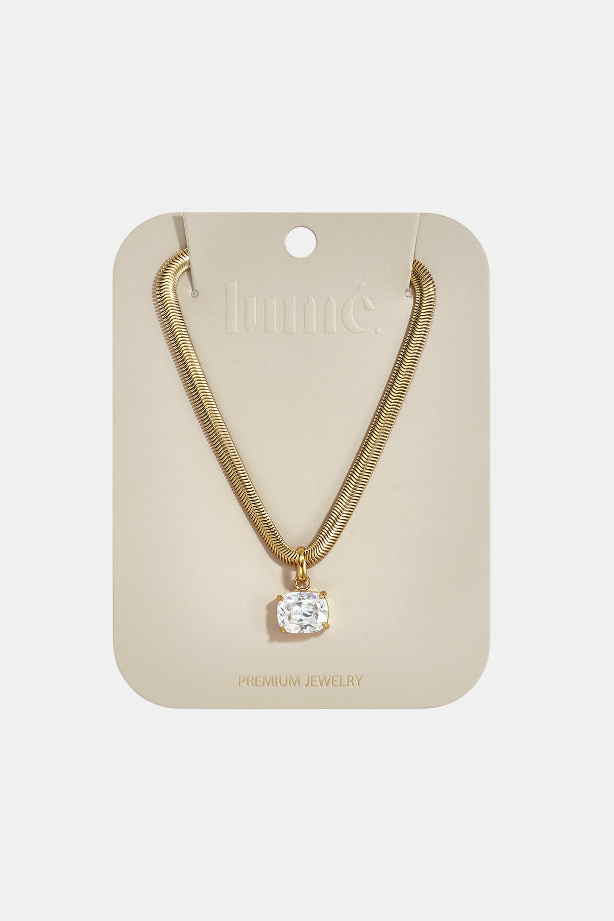 Gold snake chain necklace with a square-cut clear pendant on a beige card.