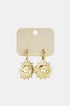 Gold-tone hoop earrings with dangling sun face charms, displayed on a cream-colored card.