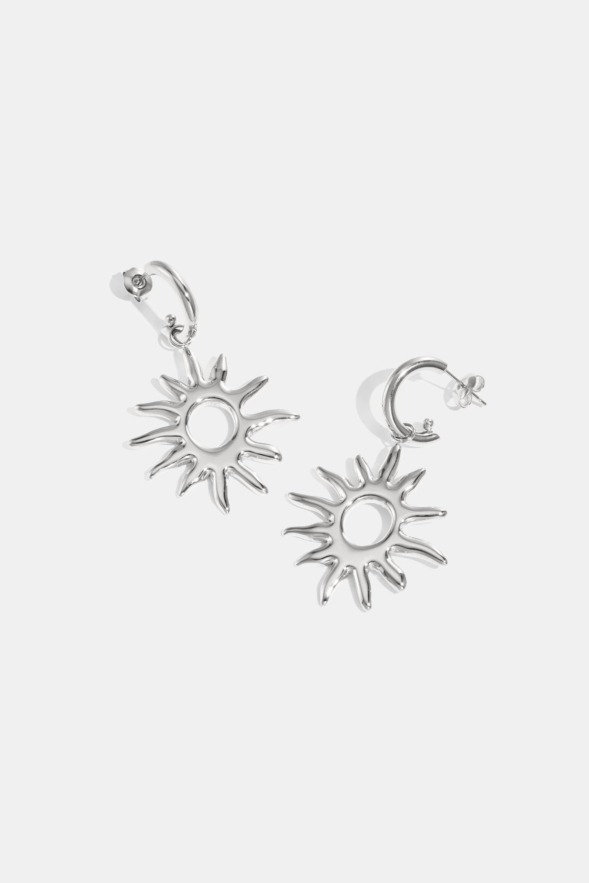 Silver sun-shaped drop earrings with pointed rays and a circular center.