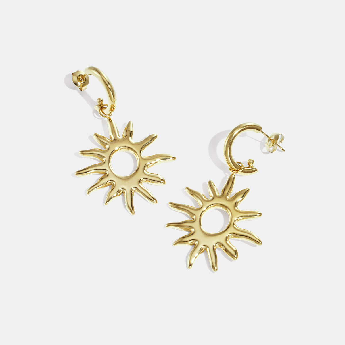 Gold-toned sun-shaped drop earrings with pointed rays and a circular center.