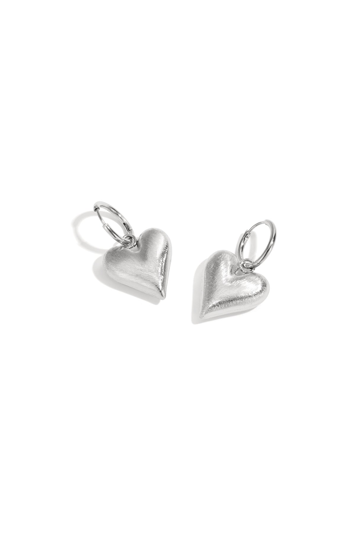 Silver heart drop earrings with hoop closures on a white background.