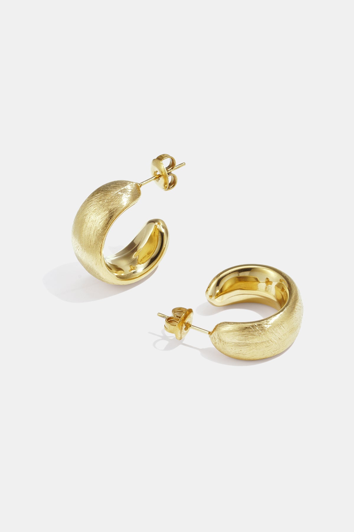 A pair of brushed gold hoop earrings with a subtle sheen, displayed on a white background.
